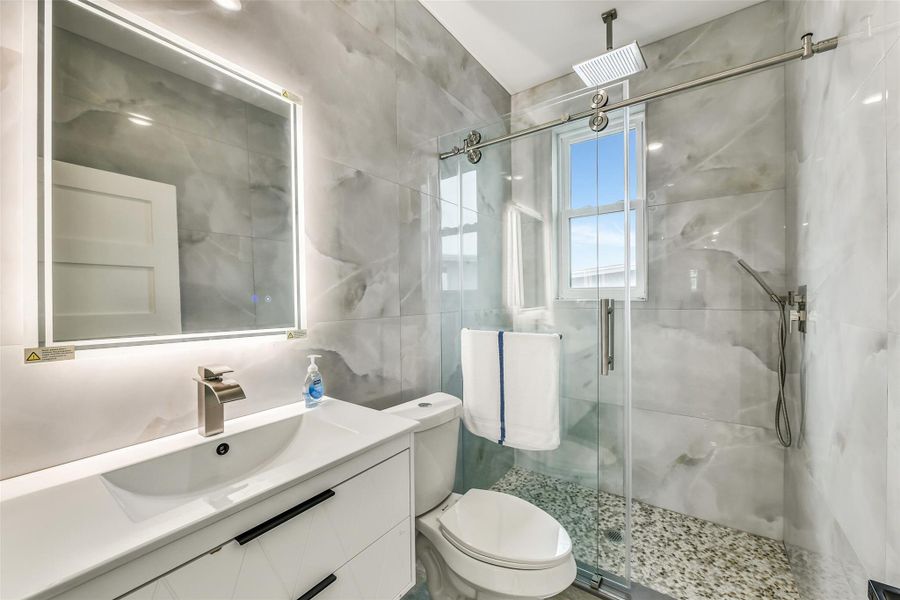 Guests enjoy a bath that feels as polished as the rest of the home. A glass enclosed shower, large format tile, and illuminated mirror combine modern style with everyday convenience. Its thoughtful design offers visitors comfort and privacy. Guests enjoy a bath that feels as polished as the rest of the home. A glass enclosed shower, large format tile, and illuminated mirror combine modern style with everyday convenience. Its thoughtful design offers visitors comfort and privacy.