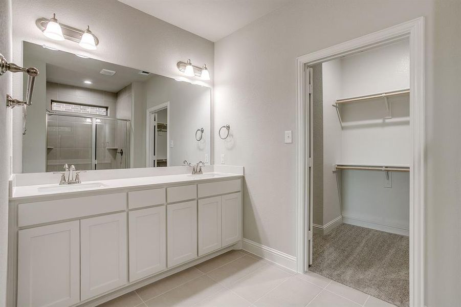 Bathroom featuring a walk in closet, double vanity, a stall shower, and light tile patterned floors Bathroom featuring a walk in closet, double vanity, a stall shower, and light tile patterned floors
