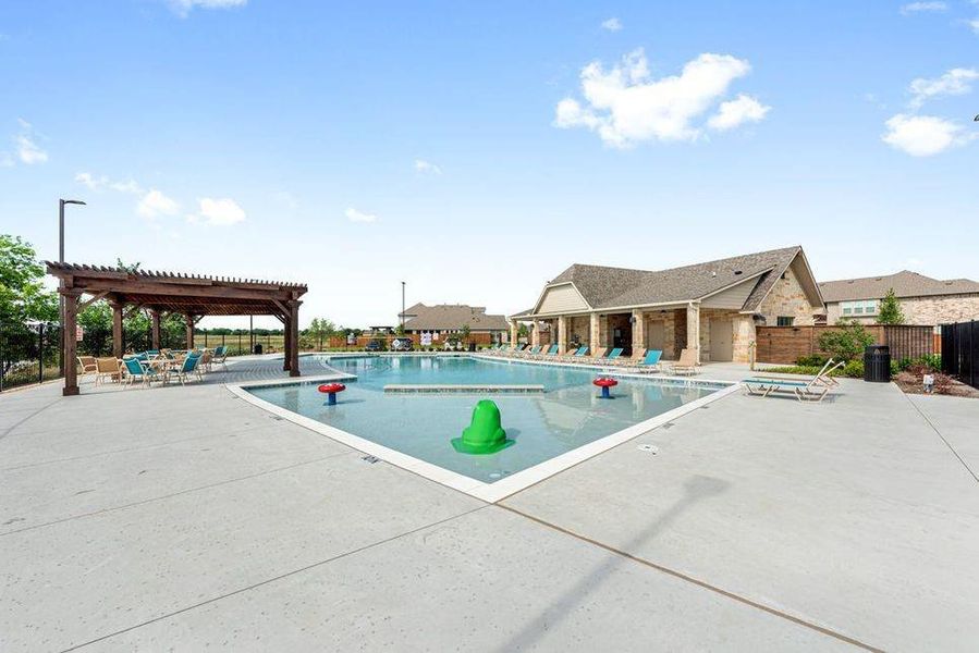 Community swimming pool with a shallow water play area, surrounded by a concrete deck