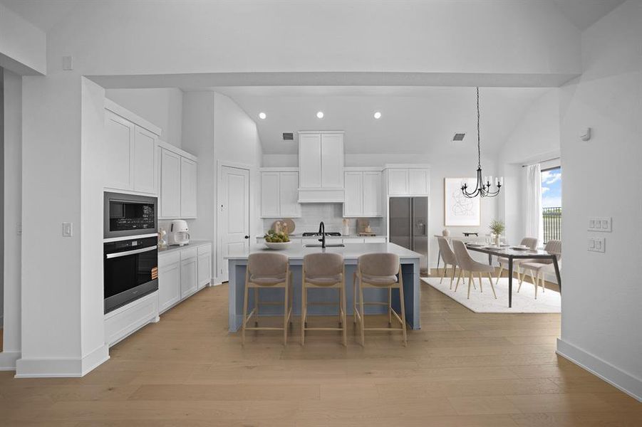 Kitchen with white cabinets, backsplash, a kitchen bar, oven, and pendant lighting