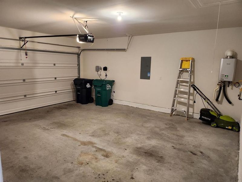 Garage featuring electric panel, a garage door opener, and water heater