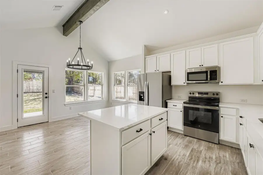 Open dining area with wood-style vinyl plank floors, a modern chandelier, and a clear view into the kitchen. Open dining area with wood-style vinyl plank floors, a modern chandelier, and a clear view into the kitchen.