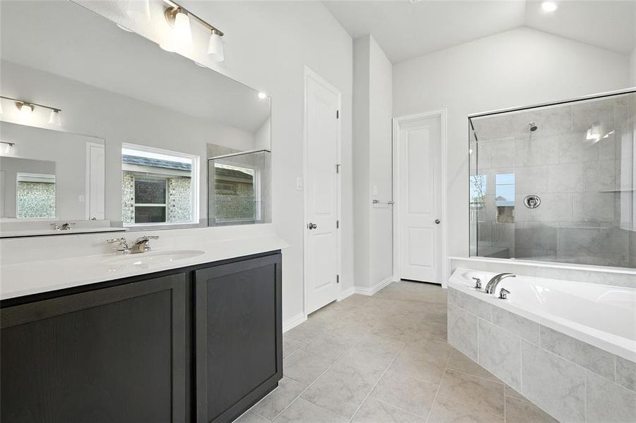 Bathroom featuring a stall shower, vanity, a bath, lofted ceiling, and tile patterned floors Bathroom featuring a stall shower, vanity, a bath, lofted ceiling, and tile patterned floors