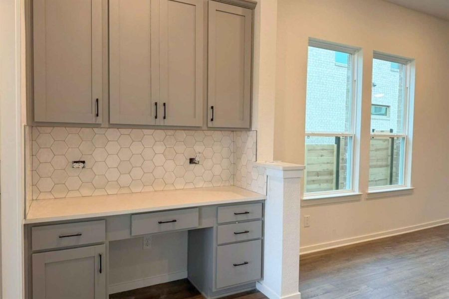 Unfurnished office with built in desk and dark wood-type flooring