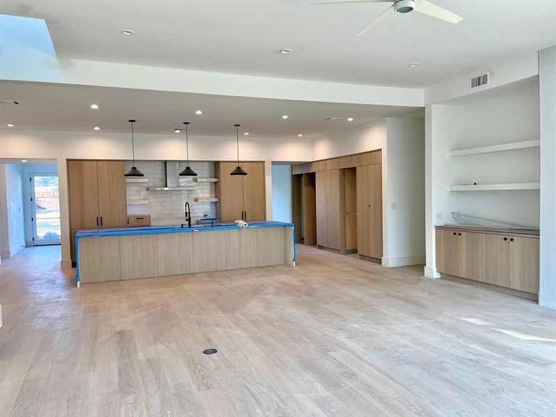 Kitchen featuring ceiling fan, a spacious island, light brown cabinetry, pendant lighting, and light hardwood / wood-style flooring