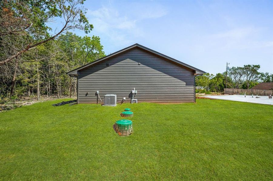 View of side of property with a lawn and cooling unit