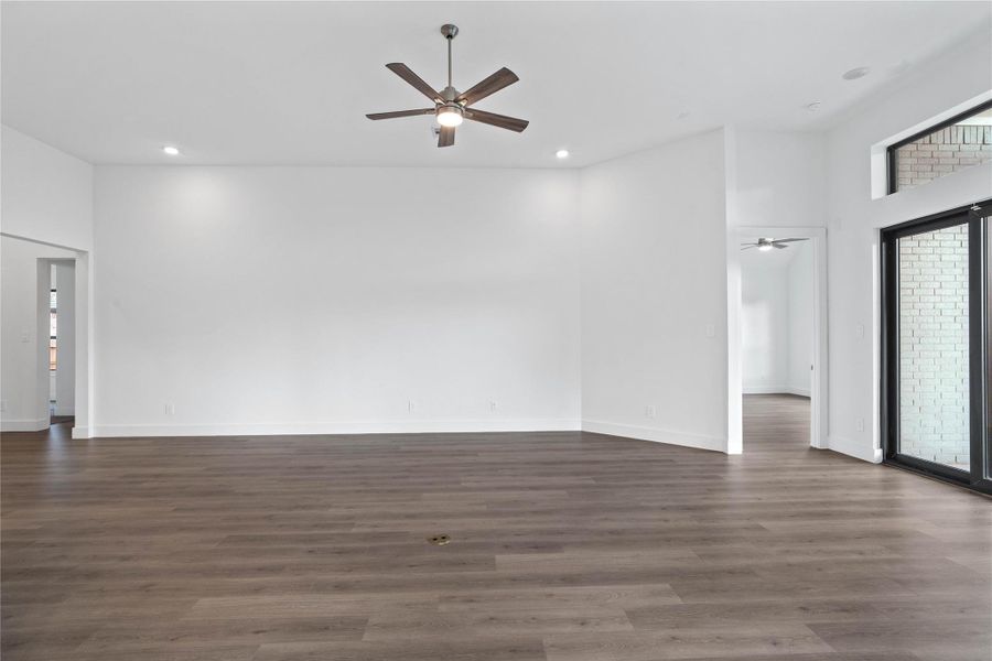 Enjoy the open and airy Family Room, designed for seamless entertaining and showcasing striking architectural details with high ceilings, recessed lighting, durable laminate flooring, and massive glass slider that bring in an abundance of natural light and seamless flow to the covered rear patio.