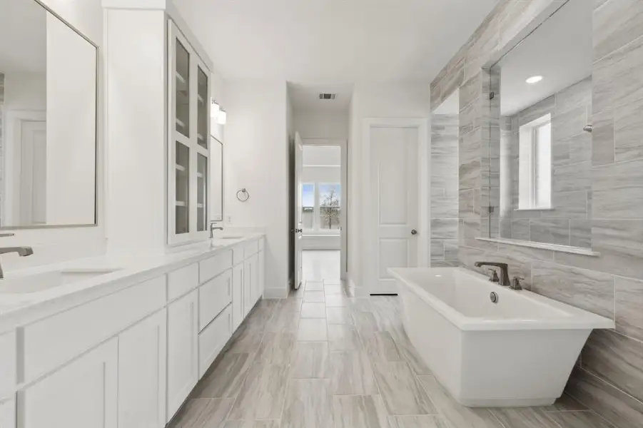 Spacious bathroom featuring a freestanding soaking tub, dual vanity with undermount sinks, and extensive tiled walls Spacious bathroom featuring a freestanding soaking tub, dual vanity with undermount sinks, and extensive tiled walls