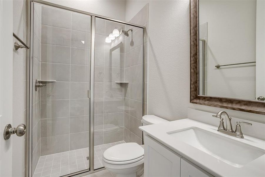 Bathroom with vanity, toilet, and a shower with shower door