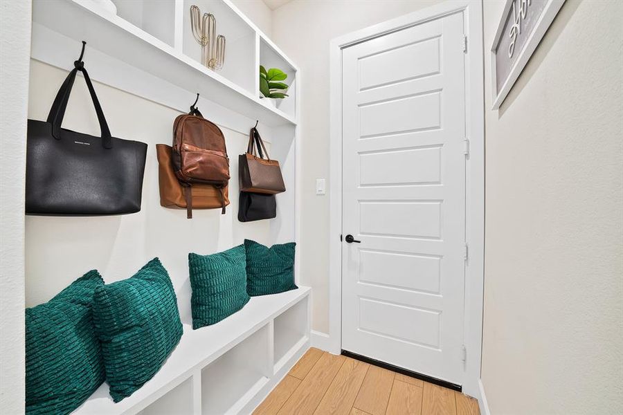 Built-in entryway storage bench with open shelving, integrated wall hooks, and wood-finish flooring Built-in entryway storage bench with open shelving, integrated wall hooks, and wood-finish flooring