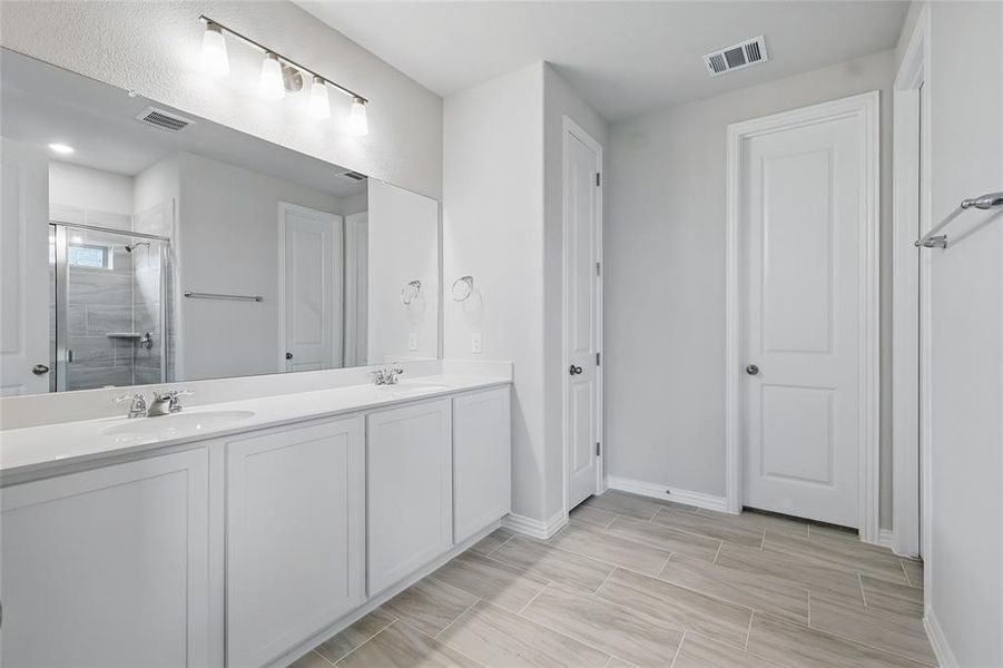 Bathroom featuring double vanity, a shower stall, and wood finish floors