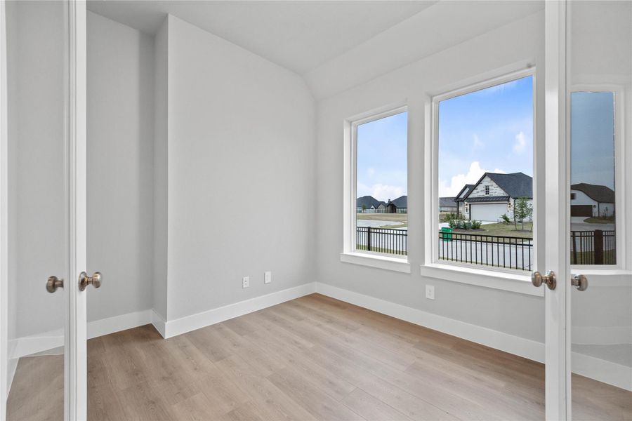 Quietly nestled in front of the home is the handsome study/home office! Featuring laminate flooring, high sloped ceiling, large windows, French doors, and custom paint!