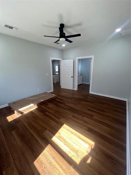 Unfurnished bedroom featuring dark wood-style floors, a textured ceiling, and ceiling fan Unfurnished bedroom featuring dark wood-style floors, a textured ceiling, and ceiling fan