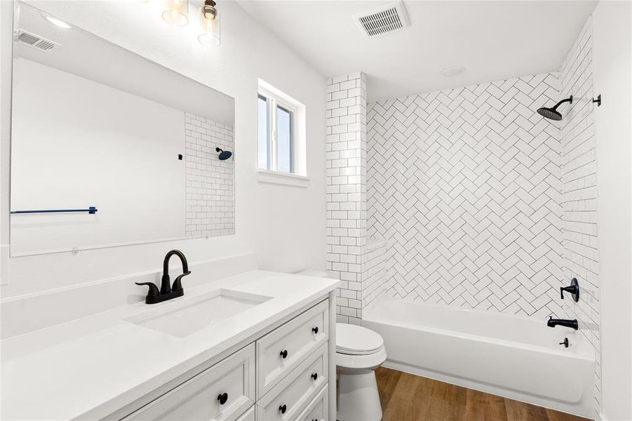 Bathroom featuring a white vanity with integrated sink, matte black fixtures, and wood-finish flooring