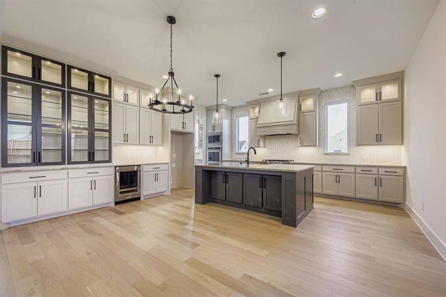 Kitchen featuring glass insert cabinets, pendant lighting, decorative backsplash, light wood-type flooring, and recessed lighting