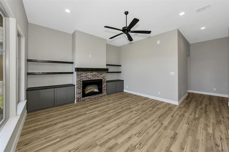 Unfurnished living room with ceiling fan, light wood-style floors, recessed lighting, and a fireplace
