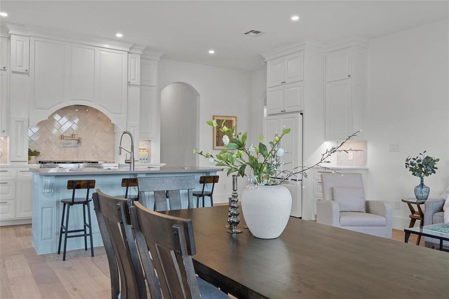 Dining space featuring light wood-type flooring, recessed lighting, and arched walkways Dining space featuring light wood-type flooring, recessed lighting, and arched walkways
