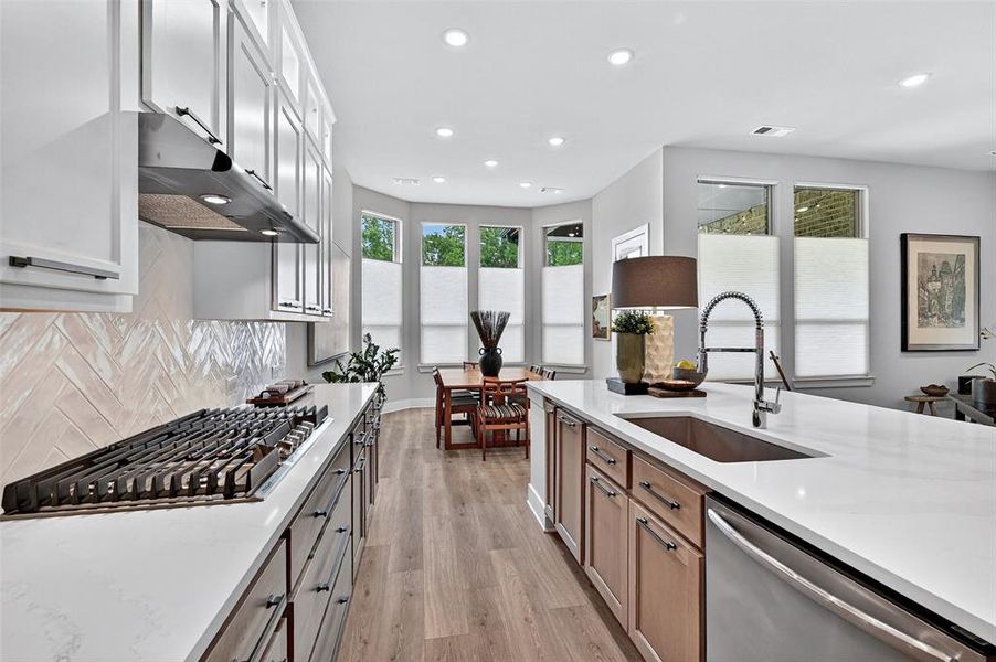 Kitchen featuring stainless steel appliances, light wood-style floors, recessed lighting, tasteful backsplash, and white cabinets Kitchen featuring stainless steel appliances, light wood-style floors, recessed lighting, tasteful backsplash, and white cabinets