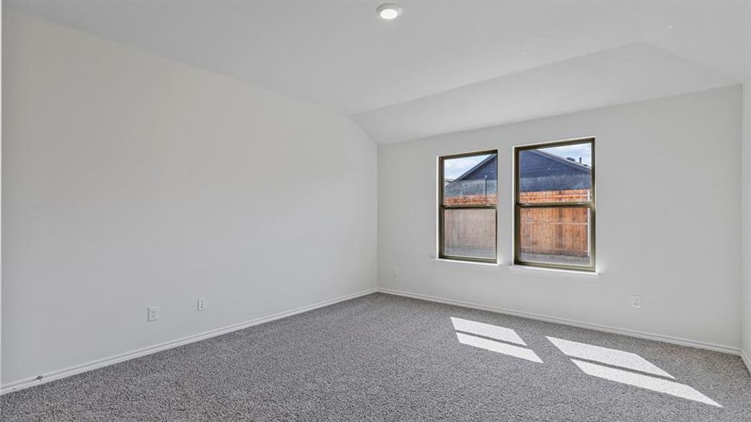 Unfurnished room featuring carpet flooring and vaulted ceiling Unfurnished room featuring carpet flooring and vaulted ceiling