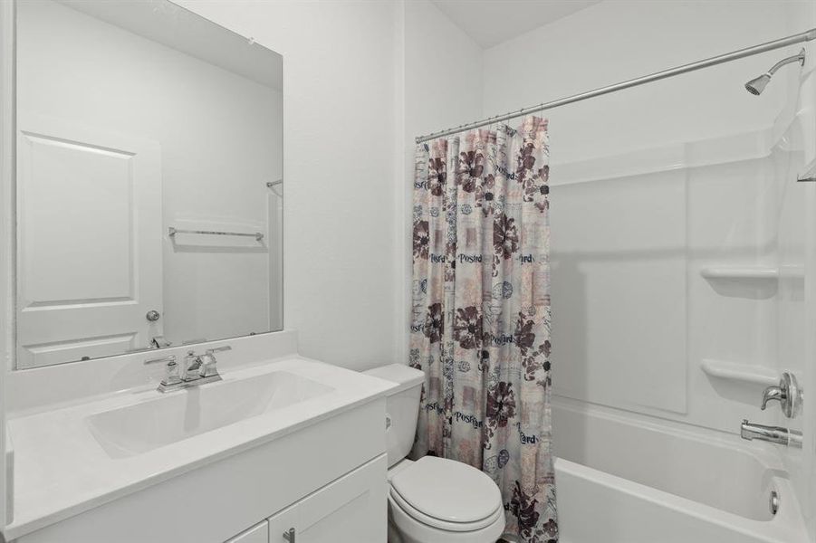 Secondary bathroom offers white countertop, sleek finishes, and tub/shower combo with tile surround.