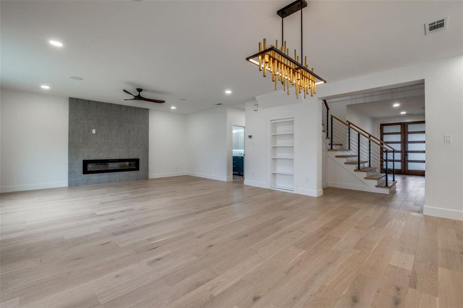 Living room featuring built in features, light wood-type flooring, stairway, recessed lighting, and a ceiling fan - Open dining area