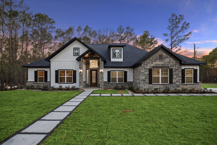Beautiful front view of the home has wood, board and batten siding along with stone and brick accents. Fully landscaped front yard.   Square slab walkway to the front door and walkway from driveway to the front door.