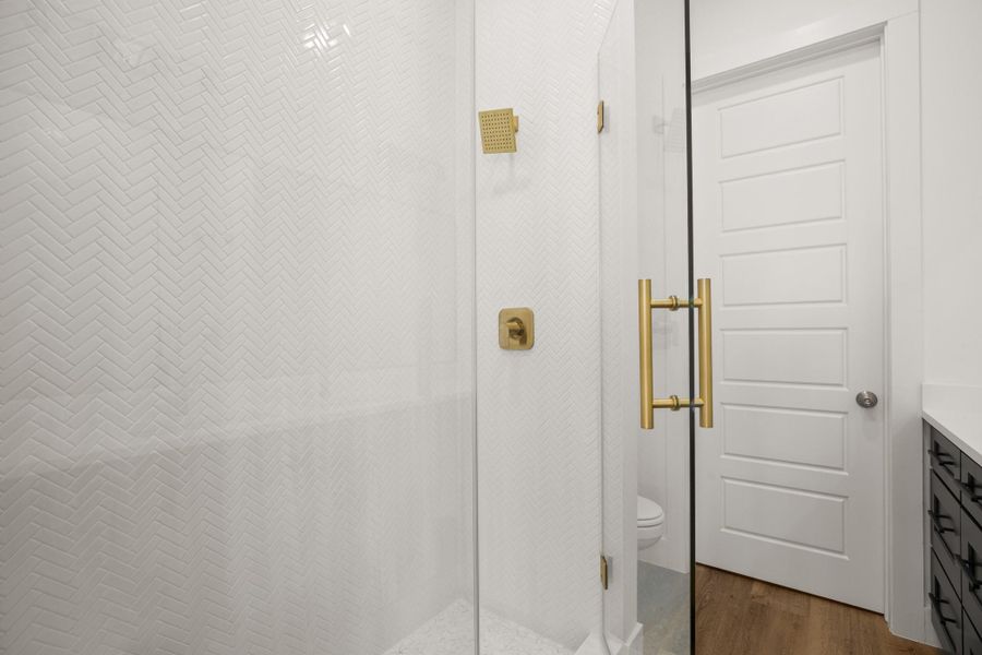 Herringbone tiled shower with brass fixtures creates a contemporary and refined bathroom space. Herringbone tiled shower with brass fixtures creates a contemporary and refined bathroom space.