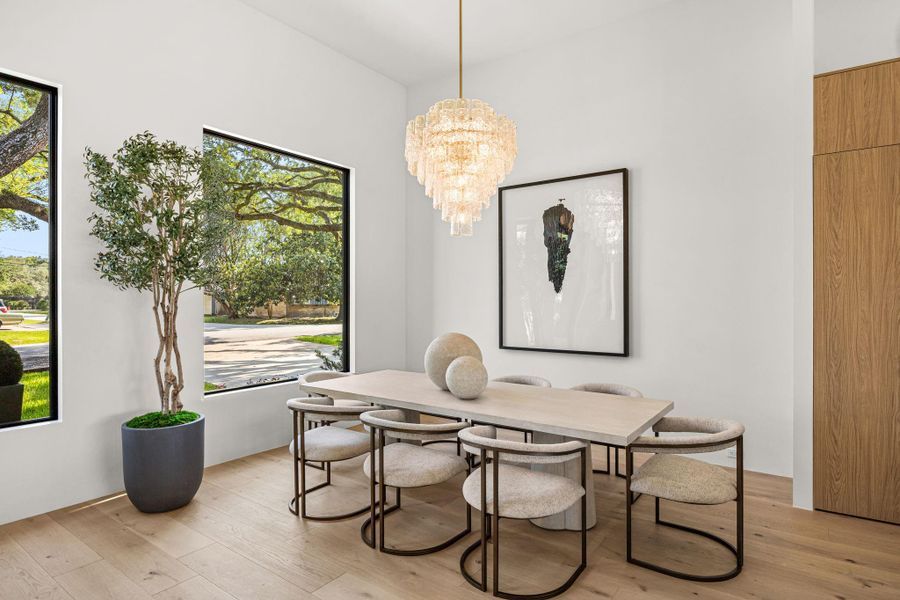 Dining Area is framed by large windows to let in natural light w/ a stunning designer selected chandelier above. Spacious for large format dining sets.