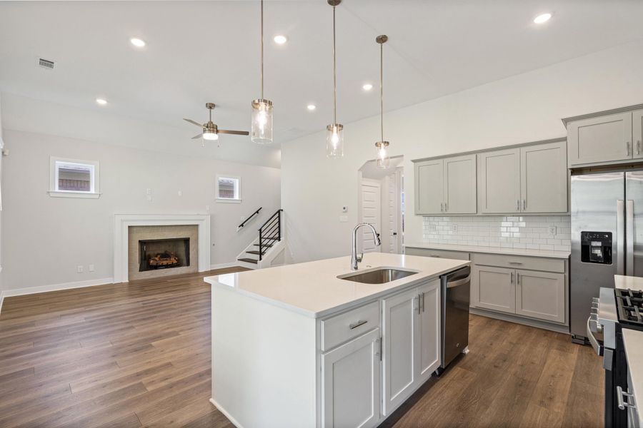 Kitchen island with an undermount sink, quartz countertop, and pendant lighting Kitchen island with an undermount sink, quartz countertop, and pendant lighting