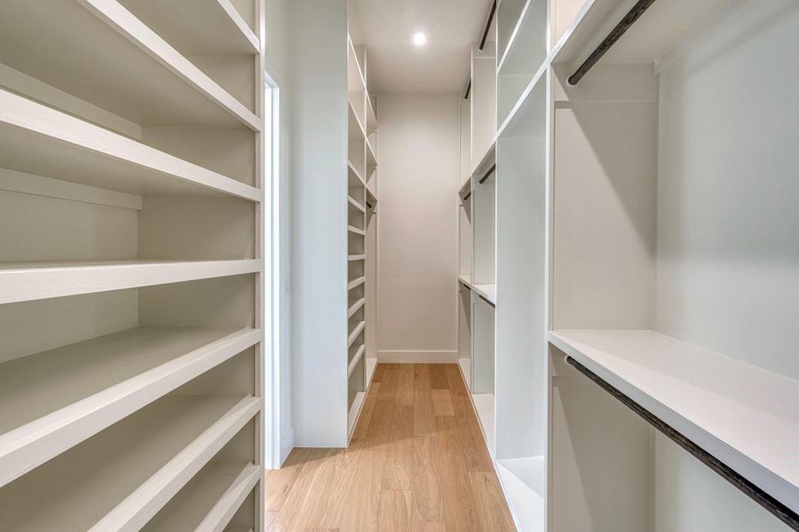Generous custom shelving and warm hardwood flooring define this organized walk-in closet space.