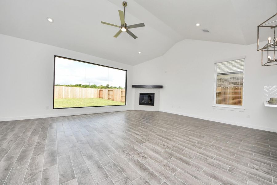 Welcome family and guests to your charming living room! With its high ceilings, recessed lighting, ceiling fan, custom paint, beautiful flooring, and large windows that let in abundant natural light, this room is perfect for gatherings. Sample photo of completed home with similar floor plan. Actual colors and selections may vary.