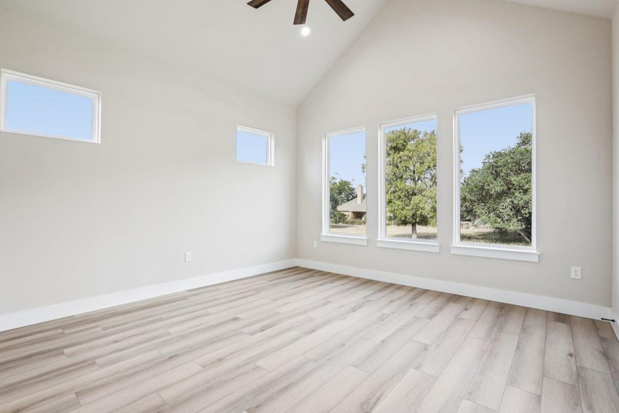 Empty room with high vaulted ceiling, light wood finished floors, a ceiling fan, and recessed lighting