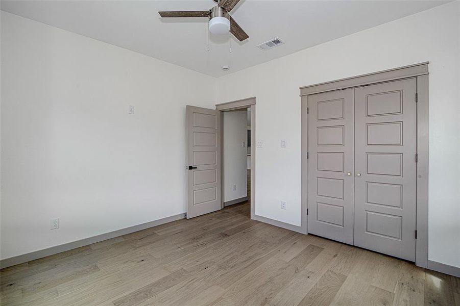 Unfurnished bedroom featuring light wood finished floors, a closet, and a ceiling fan