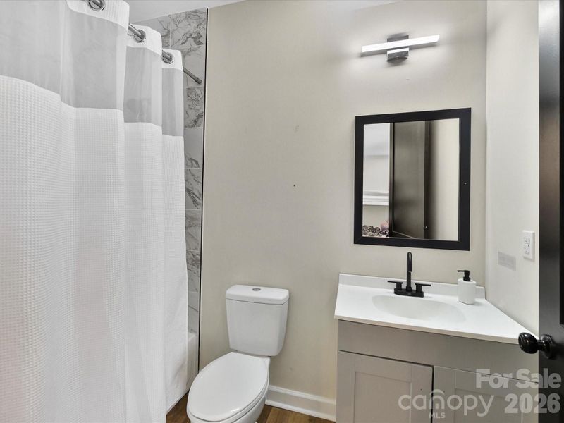 Modern ensuite bathroom featuring a sleek vanity, updated lighting, and a clean tub-shower combo.