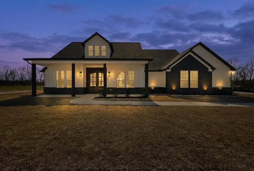 Back of house at dusk with covered porch and french doors