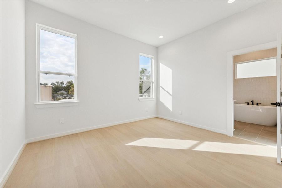 Primary bedroom with warm tones, tall ceilings, and abundant natural light, creating a serene and luxurious retreat that balances comfort and sophistication.