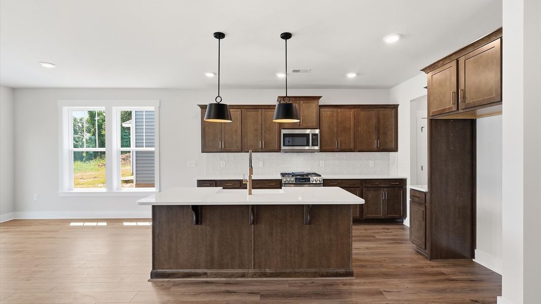 Exceptional kitchen featuring a spacious island, eye-catching pendant lights, and modern finishes by DRB Homes Exceptional kitchen featuring a spacious island, eye-catching pendant lights, and modern finishes by DRB Homes