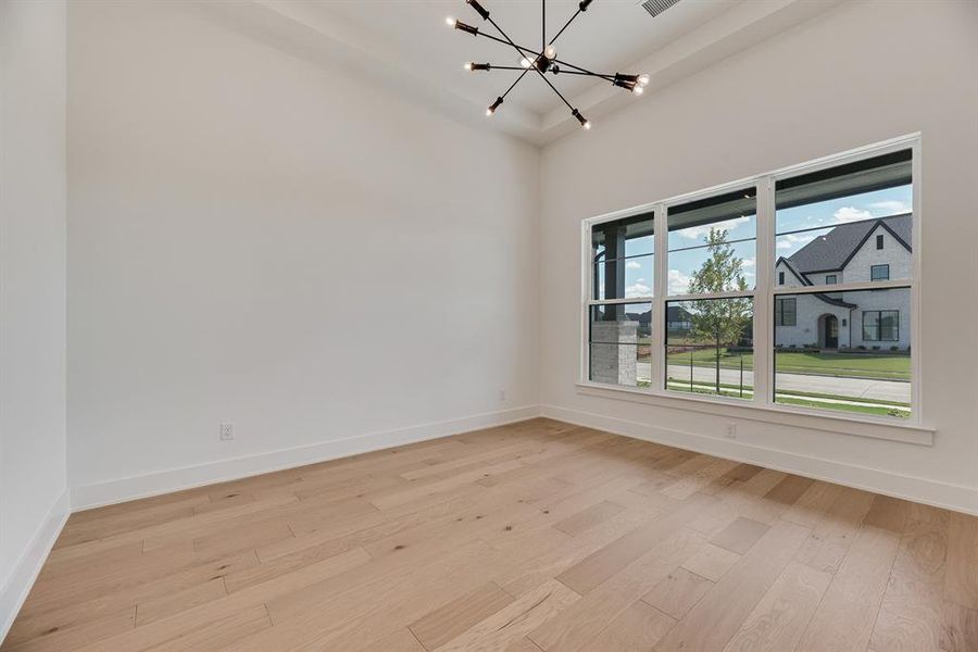Unfurnished room featuring a chandelier and light wood-type flooring
