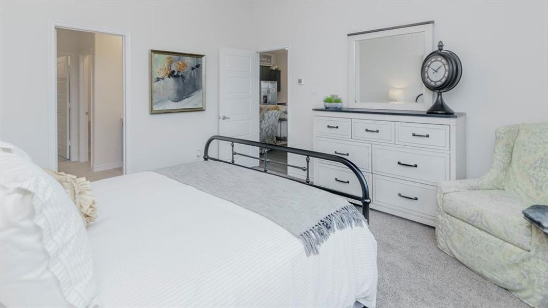 Neutral wall paint with carpet flooring, featuring a white paneled dresser with dark hardware