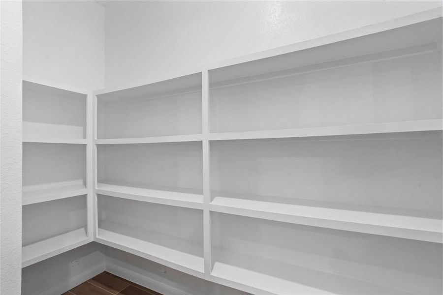 This generously sized walk-in pantry offers abundant storage with built-in, custom shelving. The crisp, clean design ensures effortless organization, making it the perfect extension of your gourmet kitchen.