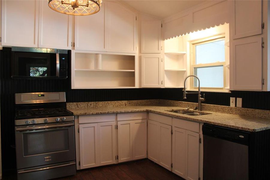 Kitchen featuring stainless steel appliances, white cabinets, light stone counters, open shelves, and dark wood-type flooring Kitchen featuring stainless steel appliances, white cabinets, light stone counters, open shelves, and dark wood-type flooring