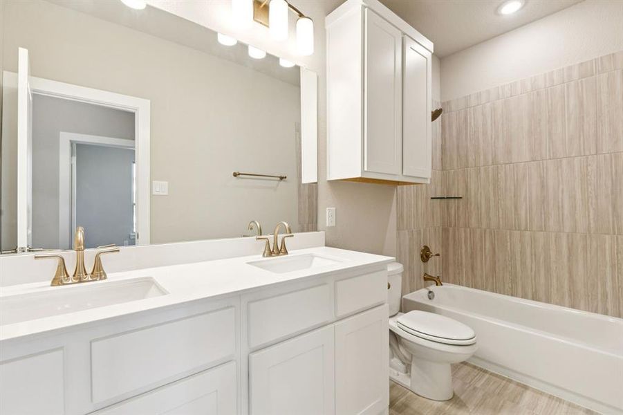 Bathroom with shower / bath combination, double vanity, light wood-type flooring, and recessed lighting