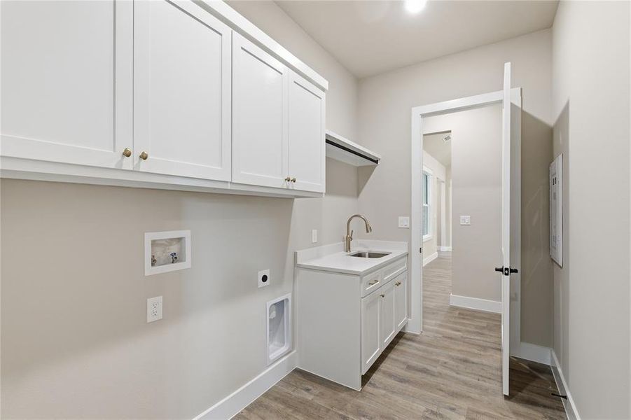 Dedicated utility space featuring a built-in sink with a gooseneck faucet, white shaker cabinetry, wood-finish flooring, and light neutral wall tones