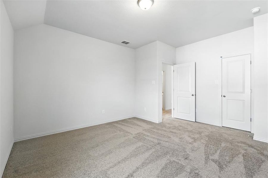 Unfurnished bedroom with light carpet and lofted ceiling