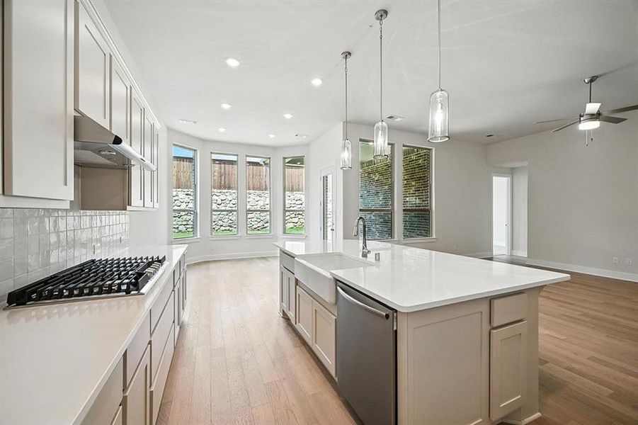 Kitchen with light wood-style flooring, appliances with stainless steel finishes, pendant lighting, open floor plan, and under cabinet range hood Kitchen with light wood-style flooring, appliances with stainless steel finishes, pendant lighting, open floor plan, and under cabinet range hood