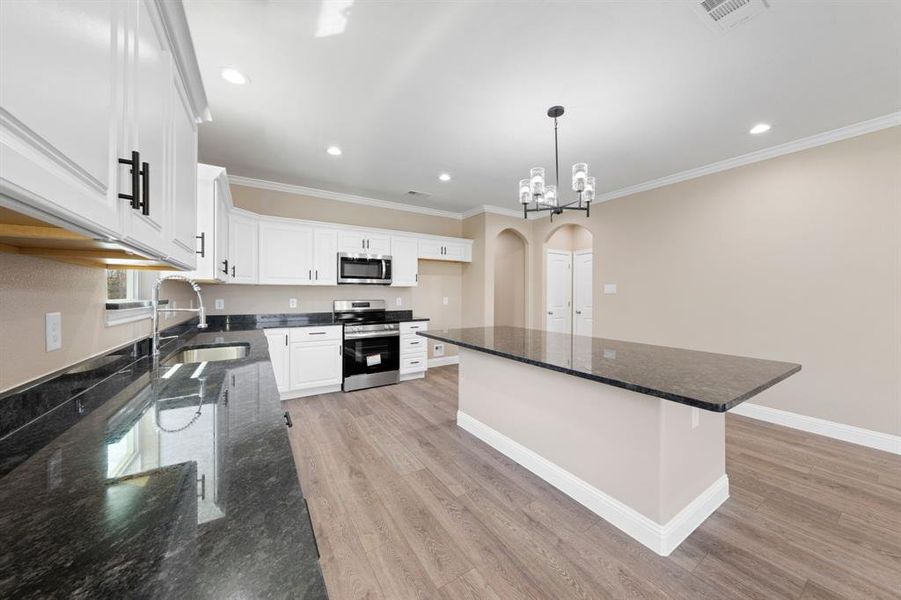 Kitchen featuring visible vents, arched walkways, light wood-style flooring, appliances with stainless steel finishes, and a sink