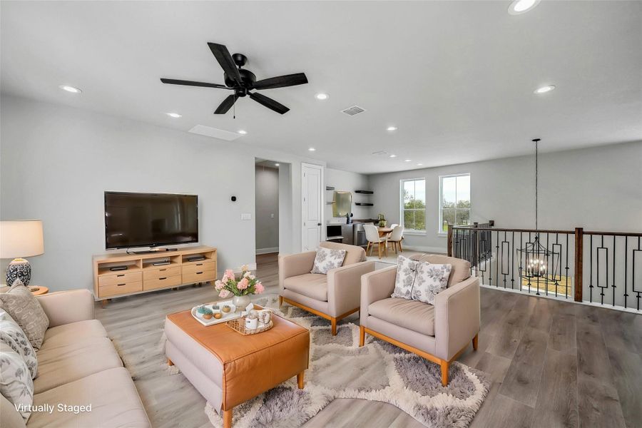 Living room with ceiling fan with notable chandelier, recessed lighting, visible vents, and wood finished floors