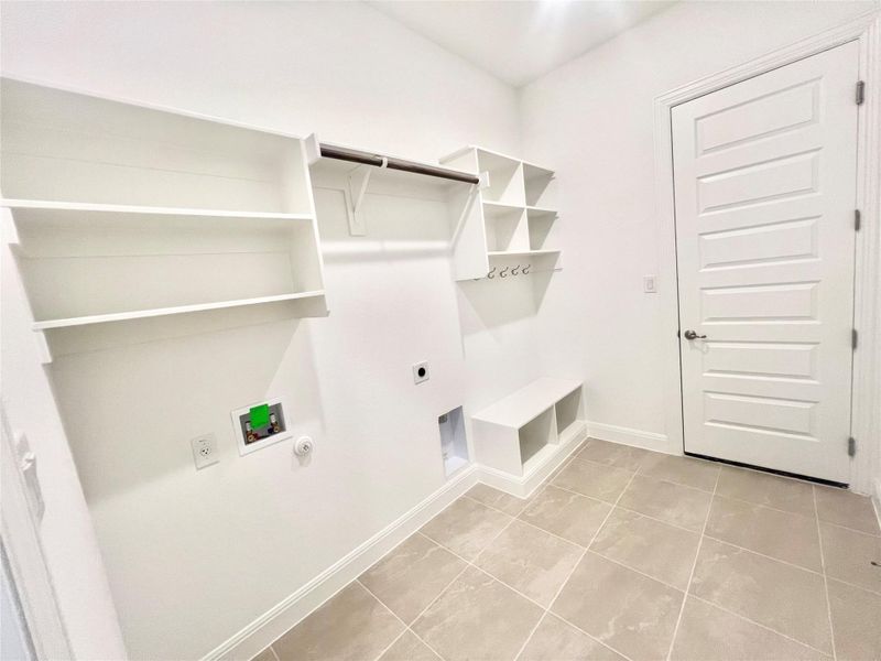 Laundry area with hookup for a gas dryer, electric dryer hookup, washer hookup, and light tile patterned flooring Laundry area with hookup for a gas dryer, electric dryer hookup, washer hookup, and light tile patterned flooring