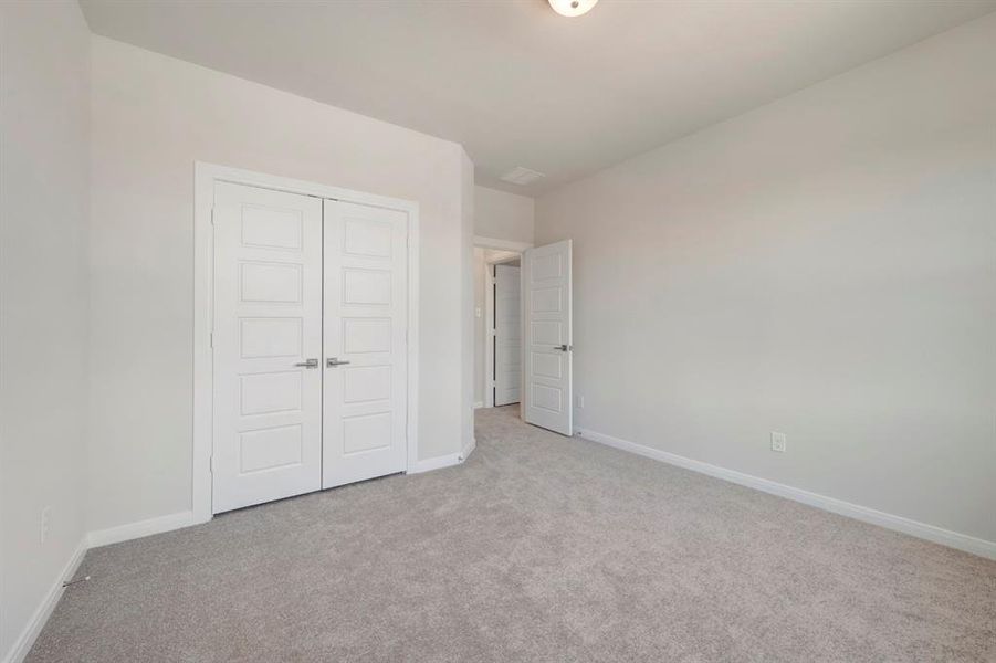 Unfurnished bedroom with light colored carpet and a closet