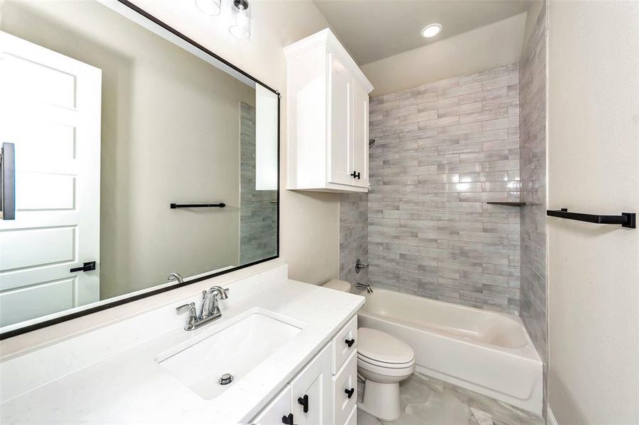 Full bathroom with vanity, tile patterned flooring, tiled shower / bath, and toilet